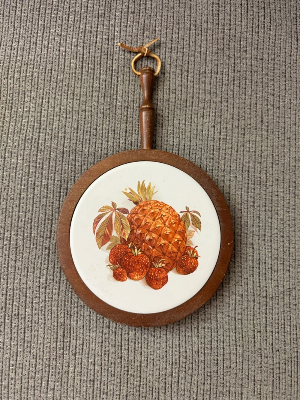 Ceramic round tile trivet pineapple/strawberries in wood hanger.
